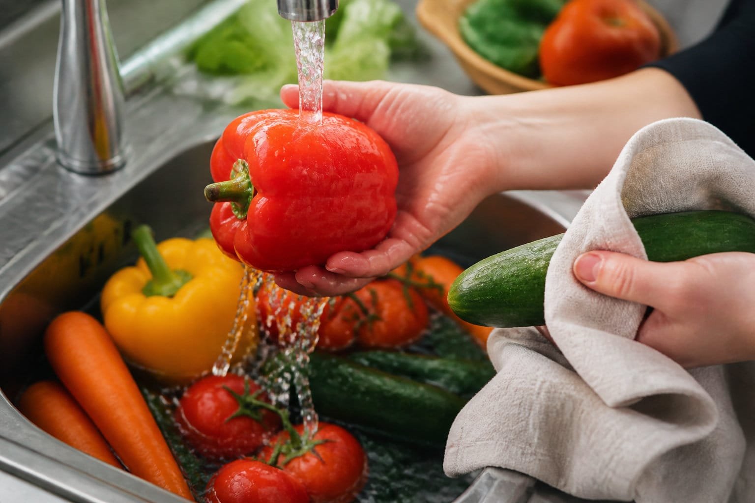 Légumes frais rincés sous le robinet avant d'être servis : poivron, concombre, carottes